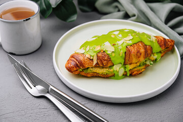 Green matcha croissant on plate with tea