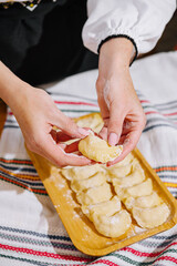 Close-up of hands shaping pierogi on a kitchen board