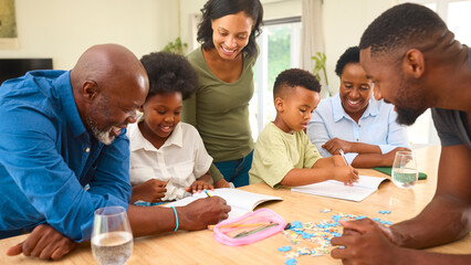 Multi-Generation Family Helping Children With Homework Sitting At Table