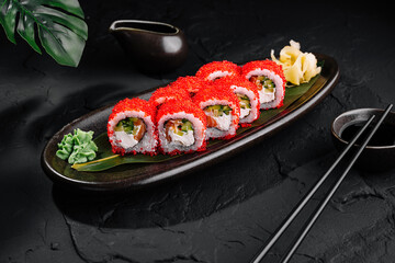 Delicious red caviar sushi roll on elegant dark plate