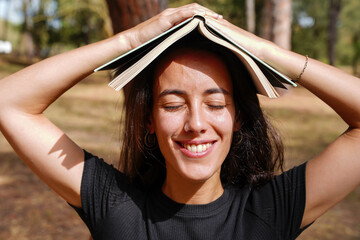 Portrait smiling adult woman with a book above the head. World book day