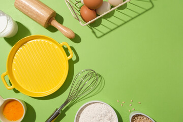 Frame of food compositions for baking cake, pastry or bread on green background from top down with a empty yellow dish to displaying product. Copy space, flat lay