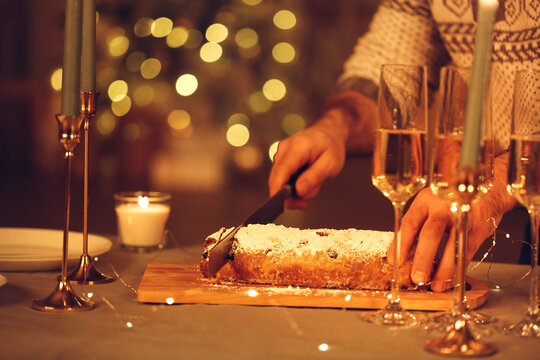 Woman cutting freshly baked homemade pie with knife, celebrating Christmas Eve with friends at home.