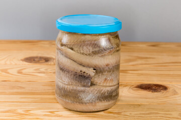 Pickled herring fillets in sealed jar on rustic table - 787046097
