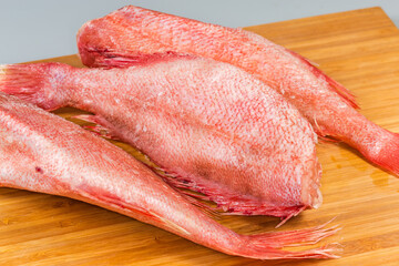 Frozen redfish carcasses with hoarfrost on cutting board, close-up - 787046248