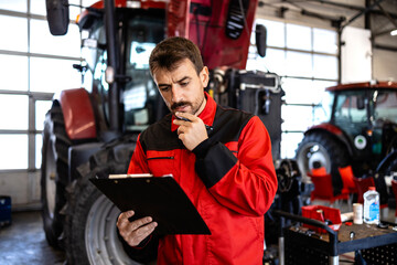 Experienced mechanic checking maintenance list of tractor agriculture machine.