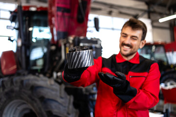Experienced serviceman holding spare parts for tractor service and maintenance.