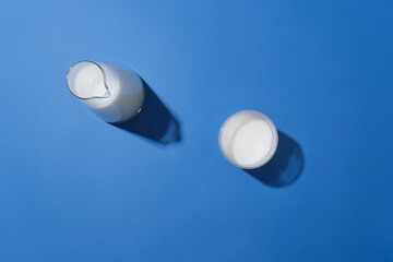 A glass of fresh milk flat lay isolated on blue background from top view. Blank space for adding...