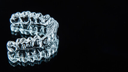 Invisible dental teeth brackets tooth aligners on black background. Plastic braces dentistry retainers to straighten teeth. - obrazy, fototapety, plakaty