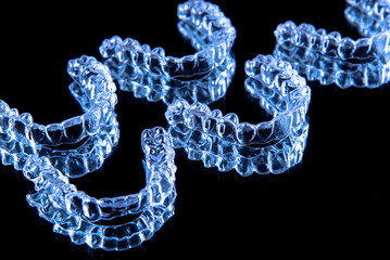 Invisible dental teeth brackets tooth aligners on black background. Plastic braces dentistry retainers to straighten teeth.