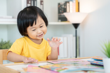 Happy Asian children relax read book at home. daughter and reading a story. learn development, childcare, laughing, education, storytelling, practice, imagine, reduce addiction mobile phone