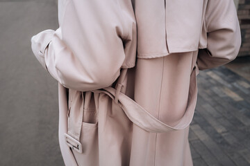 Street style fancy details of a beige women's trench coat with belt. Back view. Contemporary urban...