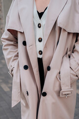 Street style fancy details of a knitted white button-up sweater and beige women's trench coat with...