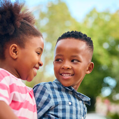 Close Up Of Smiling And Laughing Young Boy And Girl Hugging Outdoors In Countryside Or Garden
