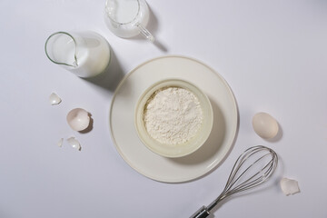 Cooking concept in minimalist style, a group of baking ingredients including milk egg and flour. Top view and blank space for displaying culinary product