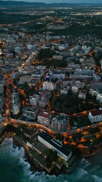 illuminated streets of Spanish touristic city Salou, Catalonia, aerial view of beach, sea and coast with palm trees, aerial drone view 4k, vertical video