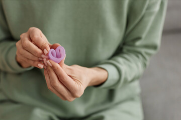 Close up of unrecognizable woman holding menstrual cup to camera and demonstrating folding technique copy space