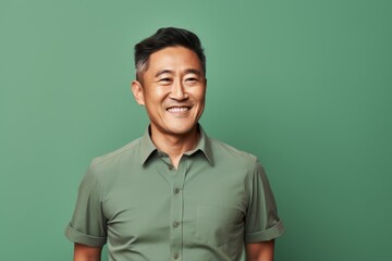 Fototapeta premium Portrait of a blissful asian man in his 40s donning a trendy cropped top isolated in pastel green background