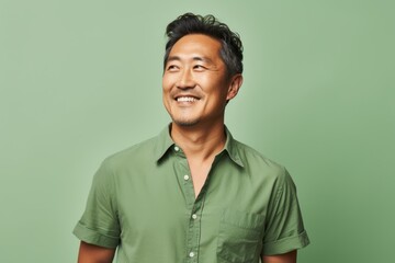 Portrait of a blissful asian man in his 40s donning a trendy cropped top on pastel green background