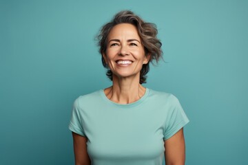 Portrait of a joyful woman in her 40s dressed in a casual t-shirt over pastel teal background