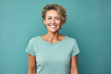 Portrait of a joyful woman in her 40s dressed in a casual t-shirt isolated on pastel teal background