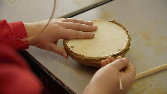 Close-up of child's hands sculping from modeling clay in a workshop.
