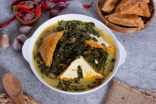 Gulai Daun Singkong, or cassava leaf curry, is made by cooking cassava leaves with coconut milk, turmeric, chili, and other herbs and spices. With the addition of tofu. 
