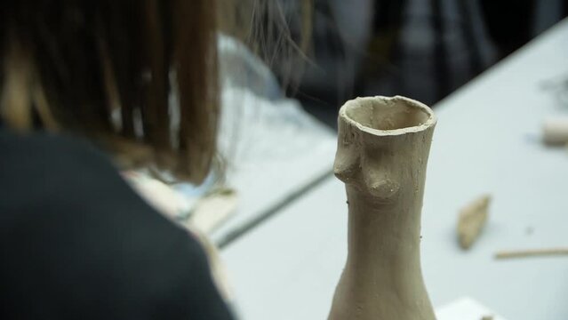 Close-up of female hands sculping from modeling clay in a workshop.