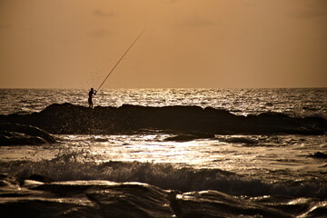 Silhouette of a man fishing on the sea