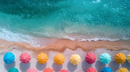 A stunning aerial view of colorful beach umbrellas lining the sandy shoreline, with clear turquoise waves gently lapping at the beach.