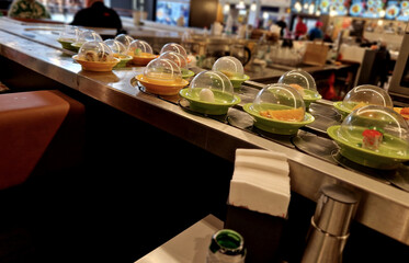 or sushi on the conveyor belt of taste of Japanese specialties. plates with sushi, maki, dim-sun...