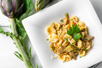 Piatto di deliziose orecchiette condite con carciofi, pasta italiana vegetariana, cibo mediterraneo  - 787069053