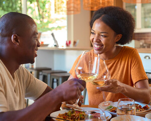 Smiling Couple Enjoying Meal At Home Together Doing Cheers With Glasses  Of Wine
