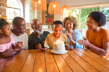 Multi-Generation Family Celebrating Grandson's Birthday At Home Blowing Out Candles On Cake