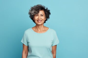 Portrait of a satisfied asian woman in her 60s dressed in a casual t-shirt in front of soft blue background
