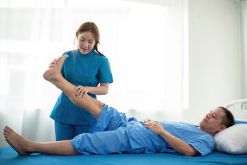 Physical therapist Asian woman, doing leg physiotherapy for elderly man to treat osteoarthritis and...