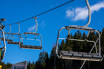 empty ski lift against the background of blue sky and fir trees. Active recreation