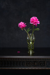 Still life with two pink peony flowers in antique glass goblet