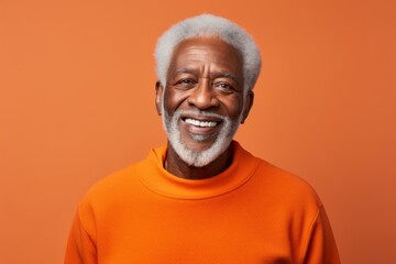 Obraz premium Portrait of a grinning afro-american man in his 80s wearing a thermal fleece pullover over soft orange background