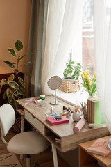 Vertical background image of small vanity table with makeup and cosmetics by window in cozy home