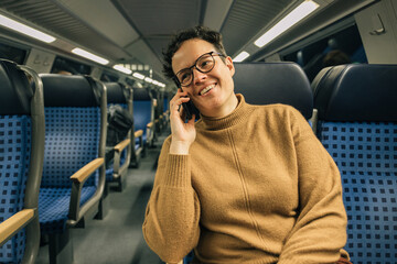 Caucasian woman smiling while talking on the cell phone while traveling by train