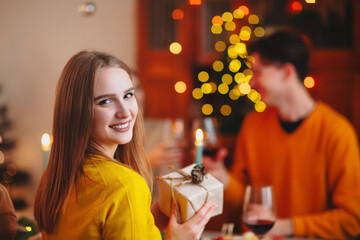 Happy smiling blond woman giving wrapped gift to friend while sitting at table
