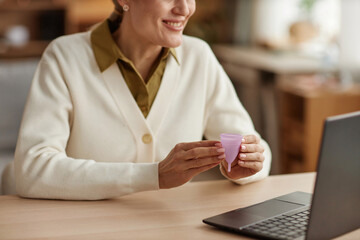Top view closeup of female health specialist holding menstrual cup while consulting client online...