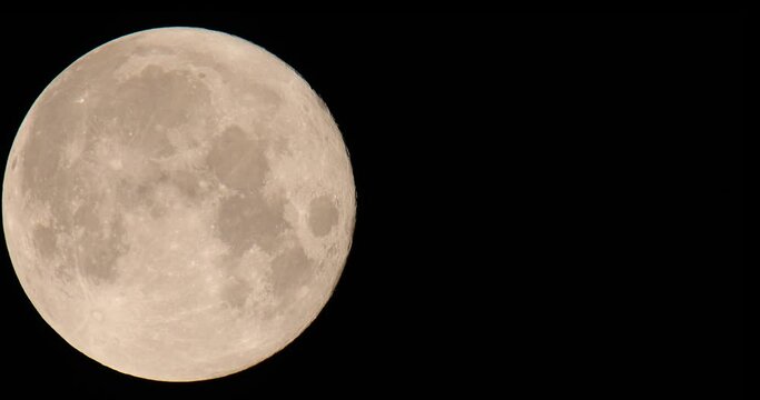 Authentic video of the movement of the full moon accelerated twice on a black background. Close-up.