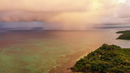 Dramatic aerial photo of rain clouds over ocean. Black clouds with rain over sea surface and coast.