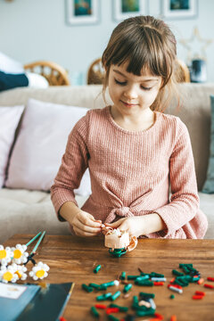 A little girl is fully engaged in her creative project, arranging small colorful construction pieces, her face lit up with excitement