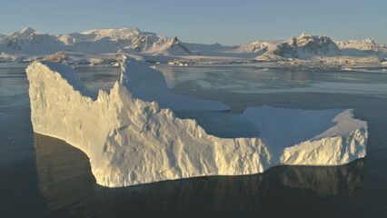 Close-up iceberg. Antarctica aerial drone view flight . Slow the sunlit iceberg with oval water...
