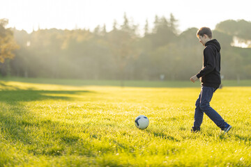 A boy is playing soccer in a field