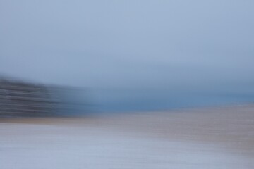 Intentional camera movement (ICM) image of seashore with reeds and ground covered with snow in...