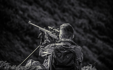 Hunting period. Hunter is aiming. The man is on the hunt. Hunter with shotgun gun on hunt. Deer hunt. Hunter in camouflage clothes ready to hunt with hunting rifle. Hunter man. Black and white